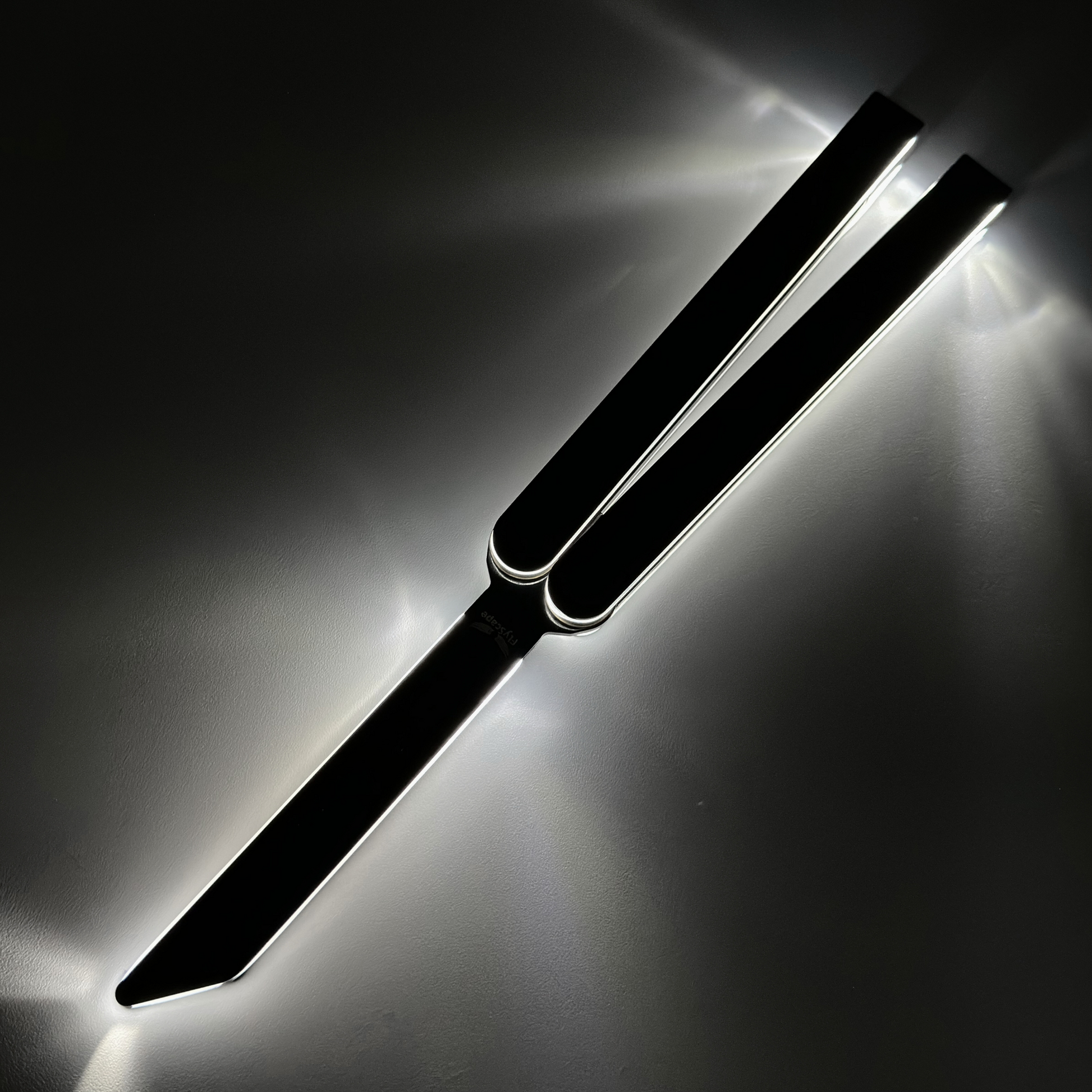 The EOS rechargeable light-up balisong with fiber optic cables in anodized black Aluminum 7075 casing. Illuminated balisong trainer with glowing edges, displayed open on a dark surface, casting bright light reflections around its outline.