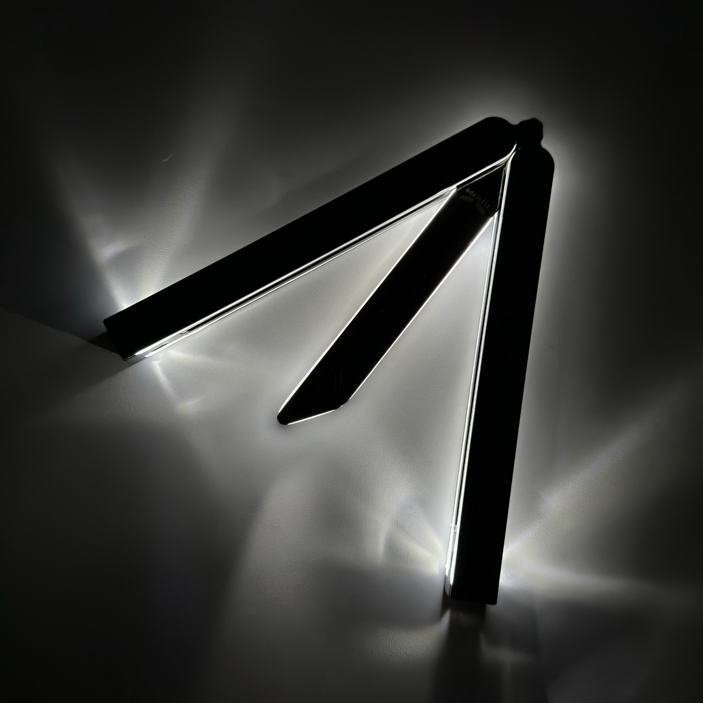 Partially open EOS balisong with fiber optic technology for visibility in darkness and an anodized black finish, casting a bright glow along the edges against a dark background, highlighting its sleek and modern design.