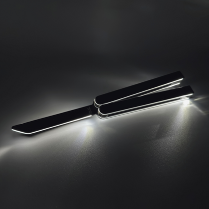 The EOS butterfly trainer fully open, showcasing fiber optic lighting in durable Aluminum 7075. Black balisong trainer with bright glowing edges, displayed in an open position against a dark background, creating dramatic light reflections and a sharp silhouette.